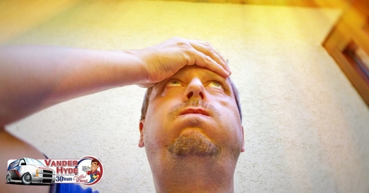A Caucasian adult man holding his hand to his head looking up at the bright sun and holding his breath