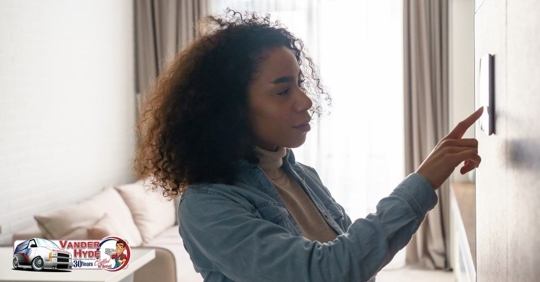 A woman holding her finger up to a wall thermostat