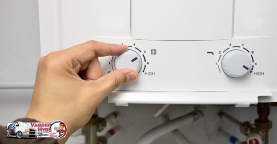 A person turning dials on a tankless water heater
