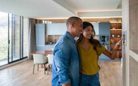 Couple looking at modern thermostat